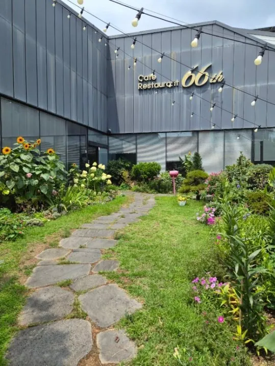 디딤돌 길이 난 앞마당 꽃밭과 줄 전구, 'Café Restaurant 66th' 간판